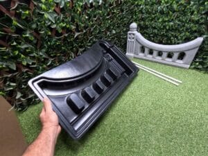 Regal Arch Mold being held by hand with finished fence panel and two included pipes shown in the background.
