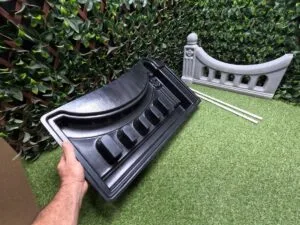 Regal Arch Mold being held by hand with finished fence panel and two included pipes shown in the background.